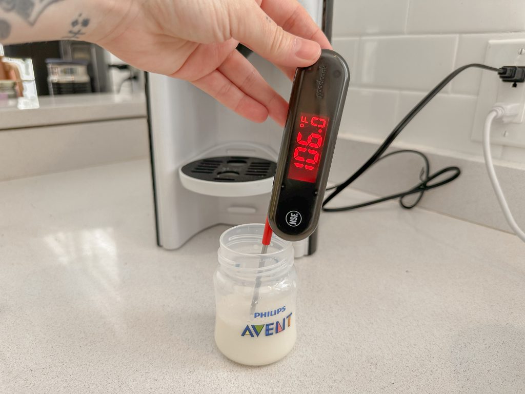 Person holding thermometer measuring 106 degrees of formula