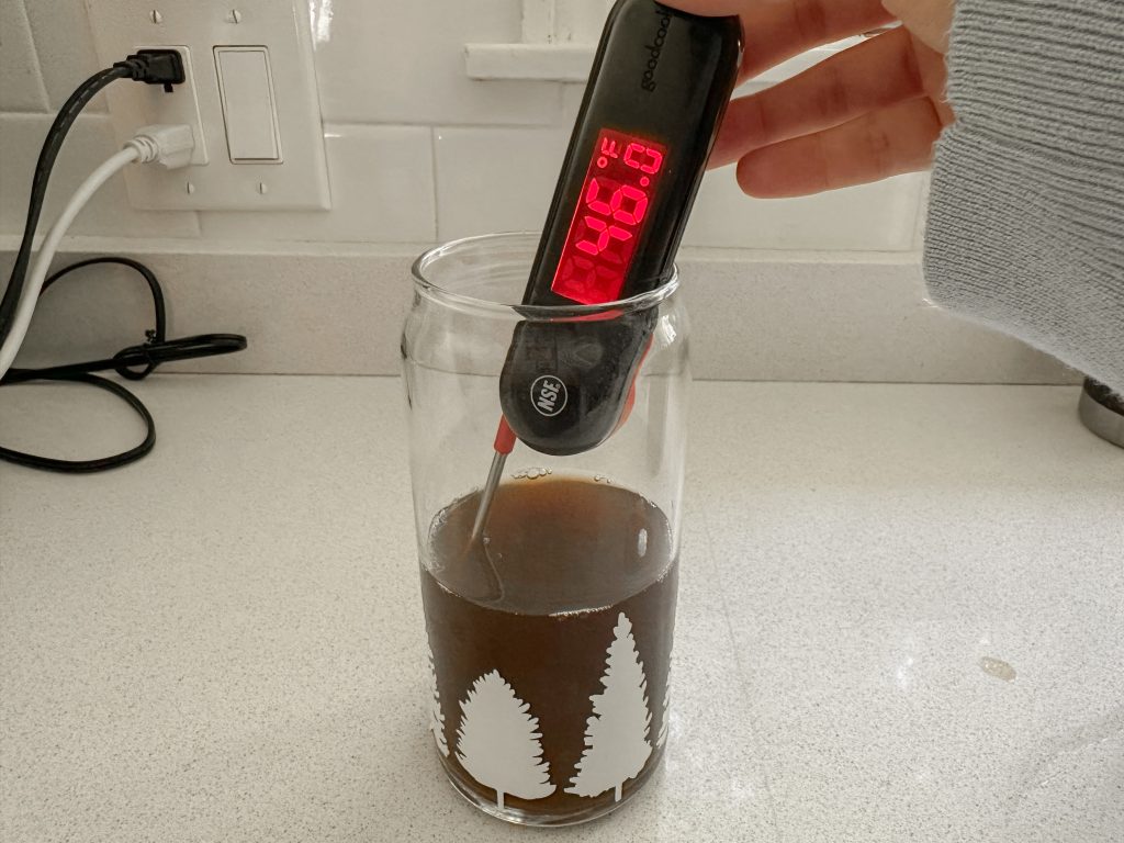 A glass cup with coffee in it and a thermometer reading 46ºF