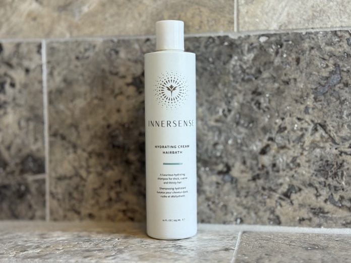 A white bottle of shampoo on a marble background.