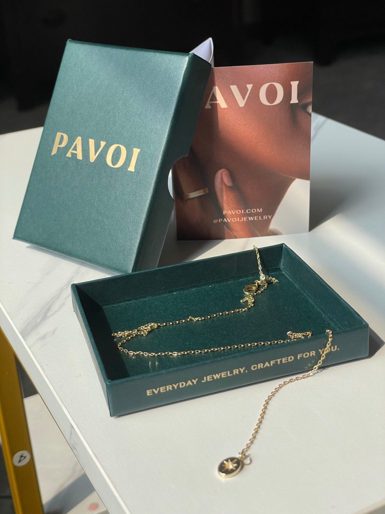 A close-up of the Pavoi necklace's packaging, including a gift box and tiny literature cards.